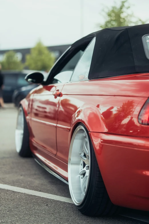 a red convertible with chrome trims parked in a parking lot