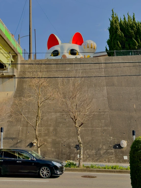 a street scene with a car driving past a large sculpture