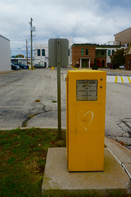 a yellow square box sitting on the corner of a street