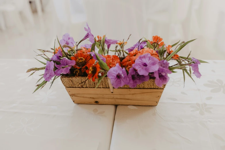 some purple and orange flowers are in a wooden box