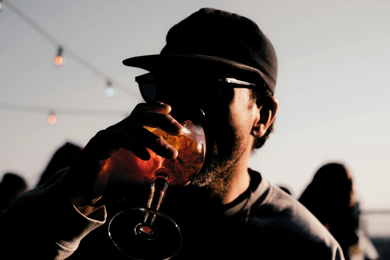 man in black hat drinking from a wine glass