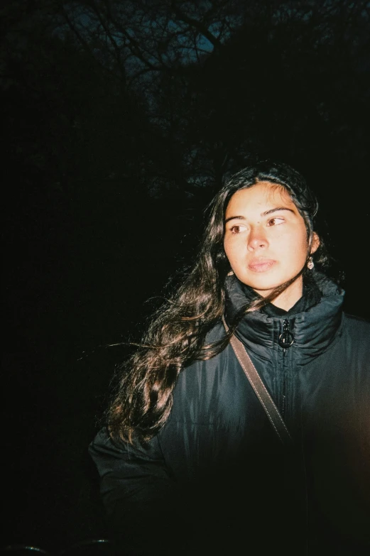 a woman with long brown hair in a park at night