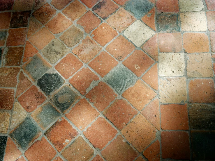 an old brick sidewalk with colored tiles and a cat