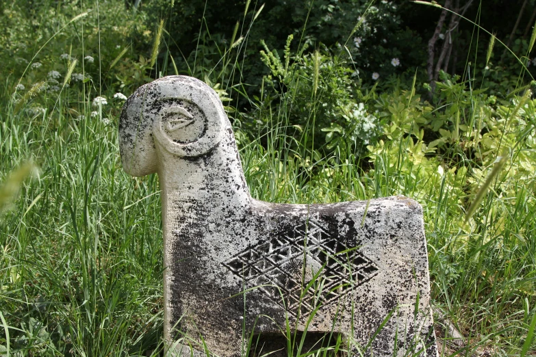 an old stone goat in some grass with its face painted