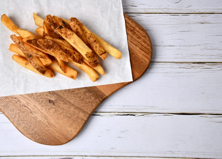 wooden tray with french fries on white wooden table