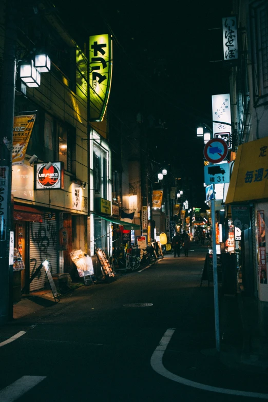 a dark city street with a few signs on the buildings