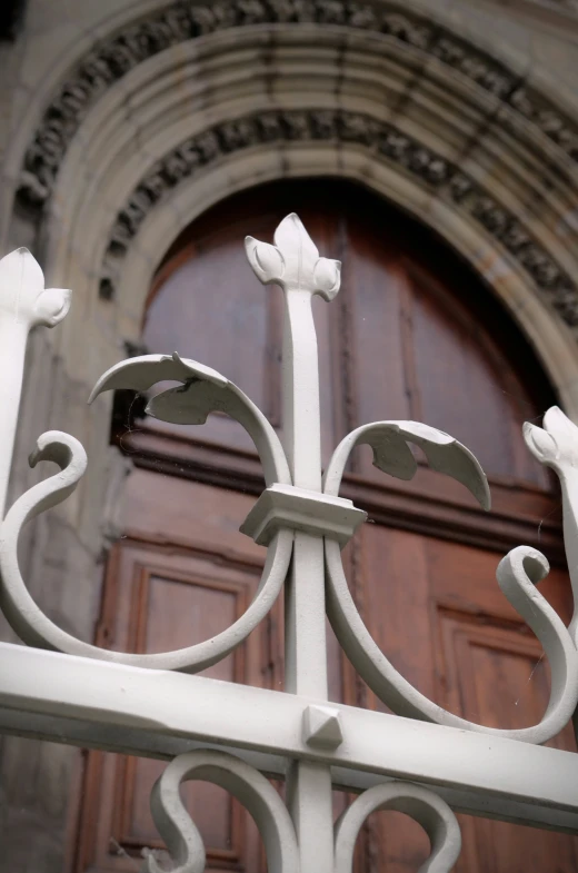 a close up of a white iron gate with a large window in the background