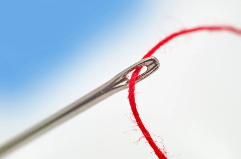 a pair of needle ends in the red thread on a white cloth