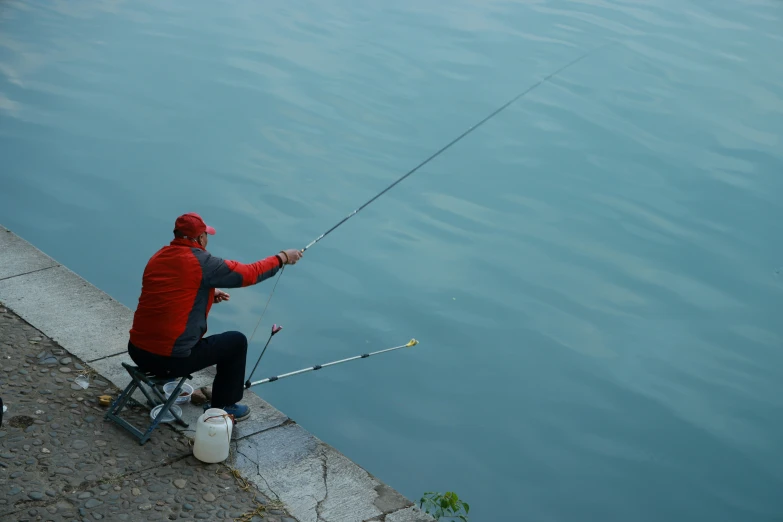 a man holding onto a pole on the side of a body of water