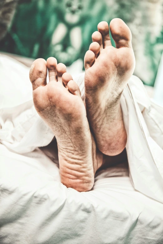 a person laying in a bed with two bare feet