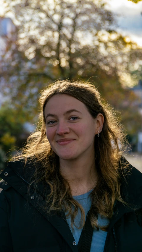 a woman smiling with a tree in the background