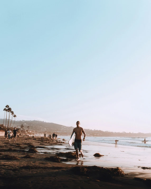 a man is walking on the beach near the water