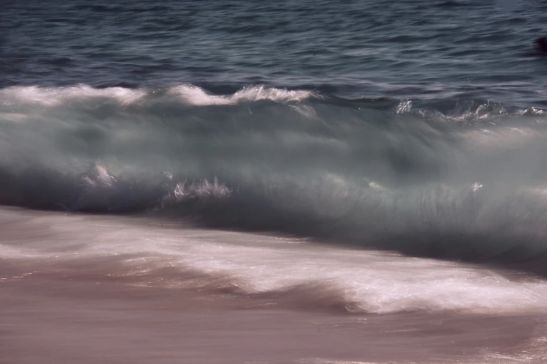 a surfer in an aqua - blue wetsuit catches a wave on the ocean