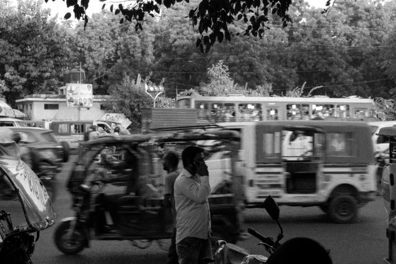 black and white image of men on street with motorcycles and cars