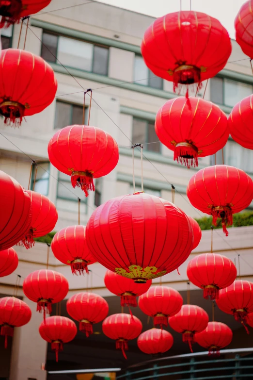 many red paper lanterns in the air near a building