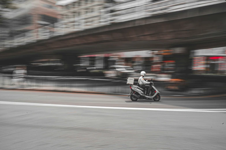 a man rides a small motorcycle down a street in the city