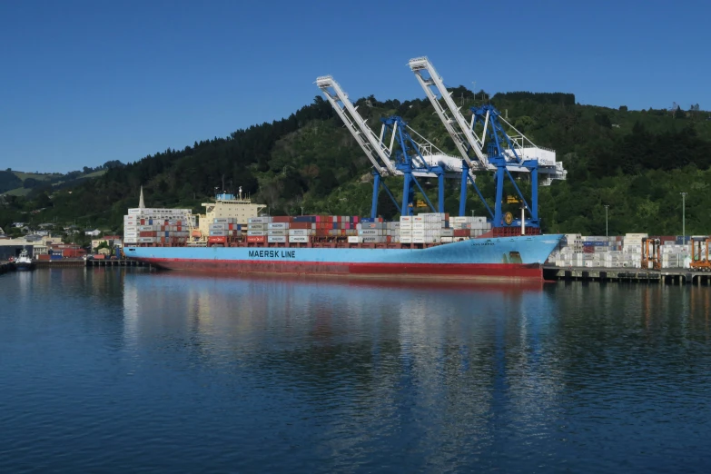 cargo ship with crane towers docked in harbor