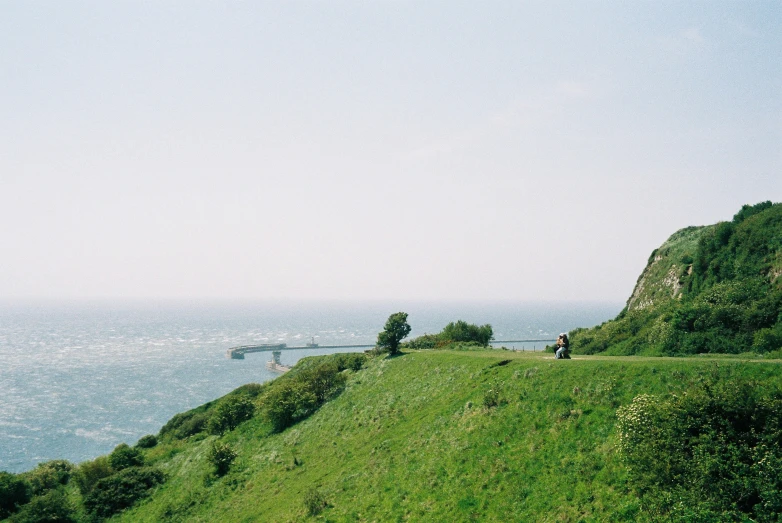 some people walking down a steep hill and a large bridge on the other side