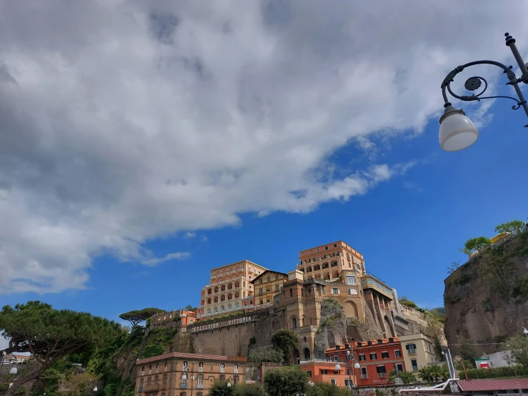 a cloudy sky is shown above some buildings on a rocky hill