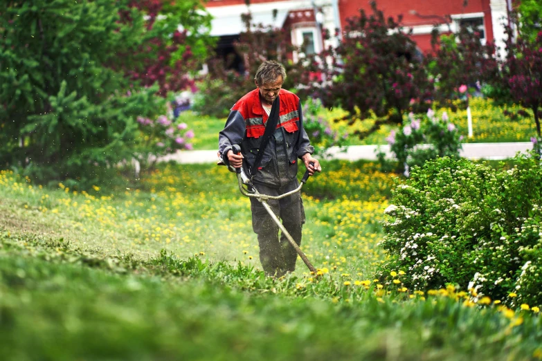 the man in red and black jacket has a mower behind his back