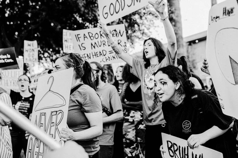 a group of women hold protest signs in front of a building