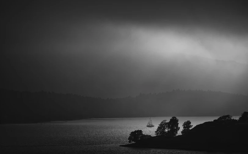 a boat on a lake in front of a dark sky with some clouds