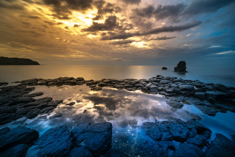 an ocean beach with rocks and a sky