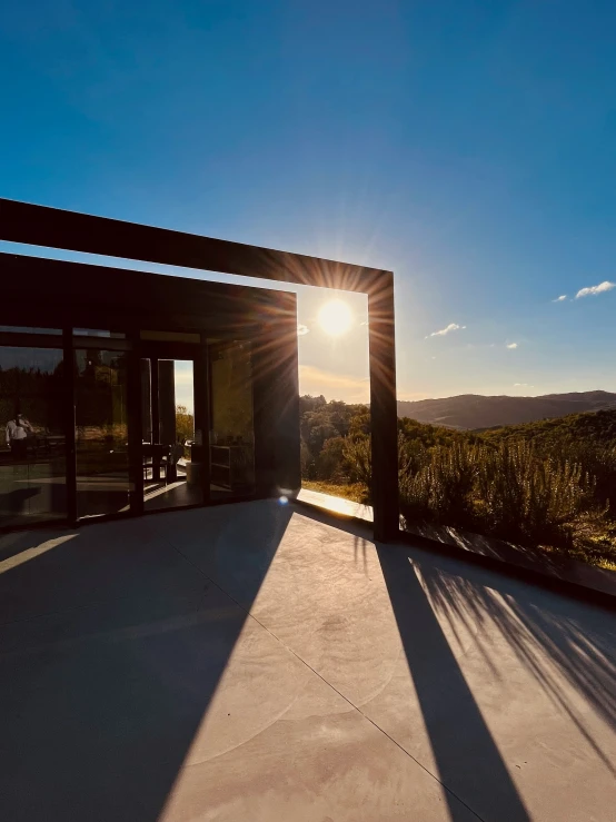 the sun shining through a metal gate that has a view of a landscape