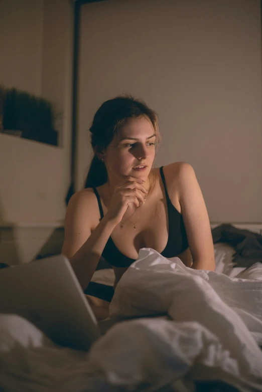 a young woman laying in bed with a laptop