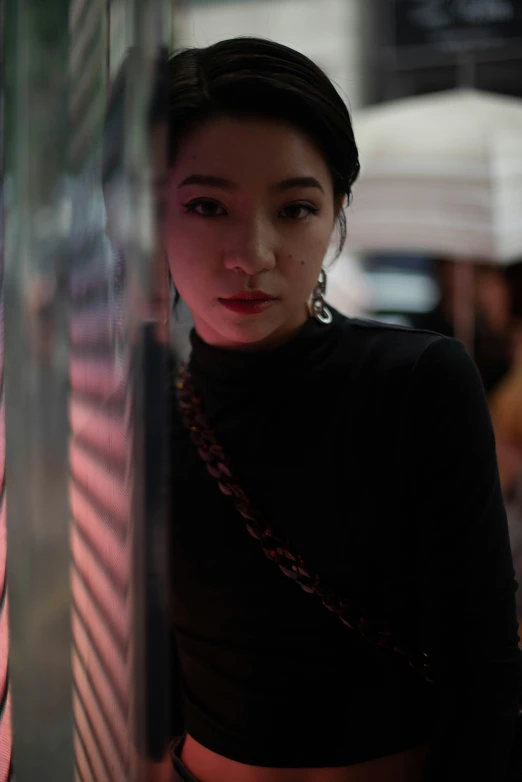 a woman standing against a pillar in front of a window