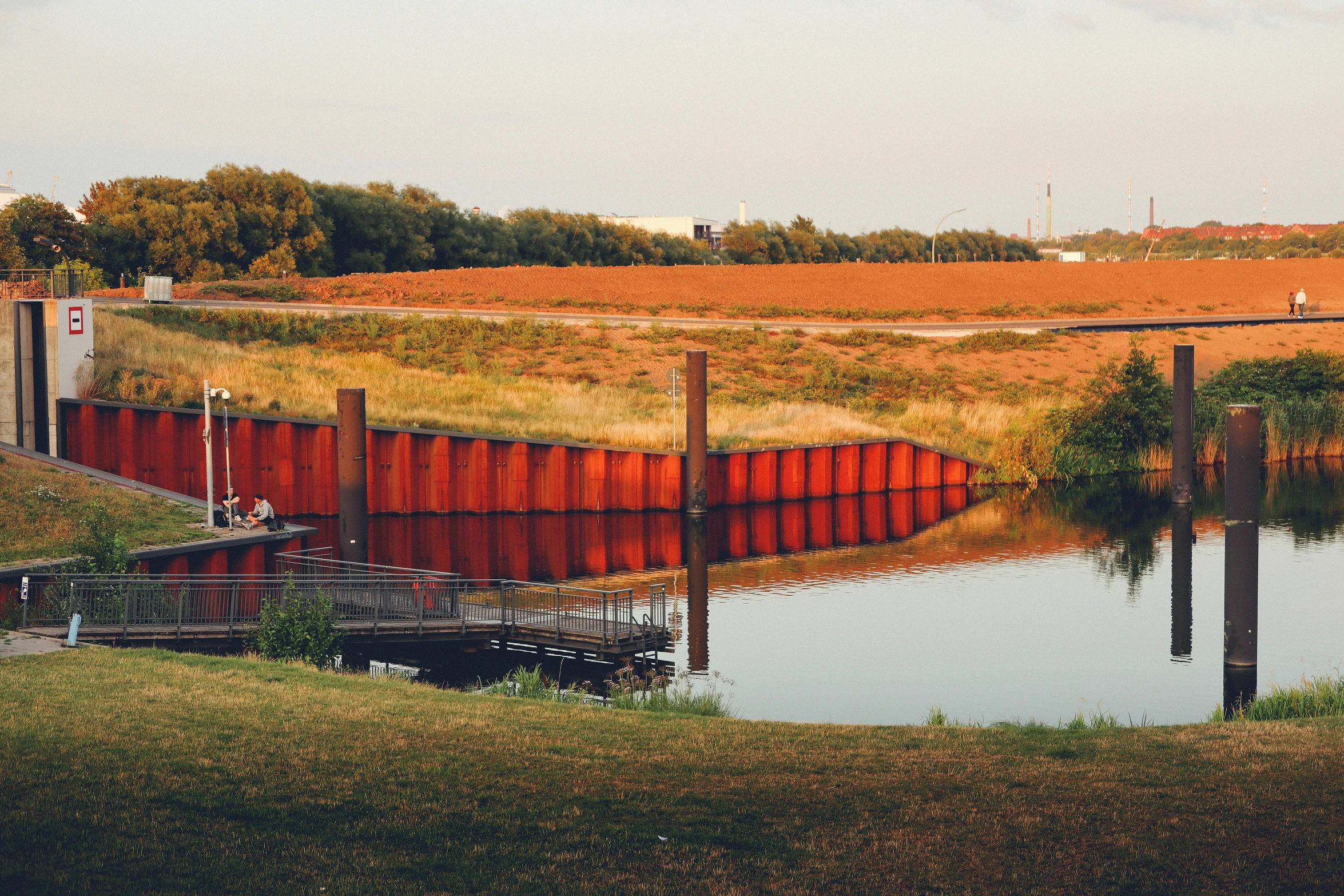 an image of a long red wall next to water