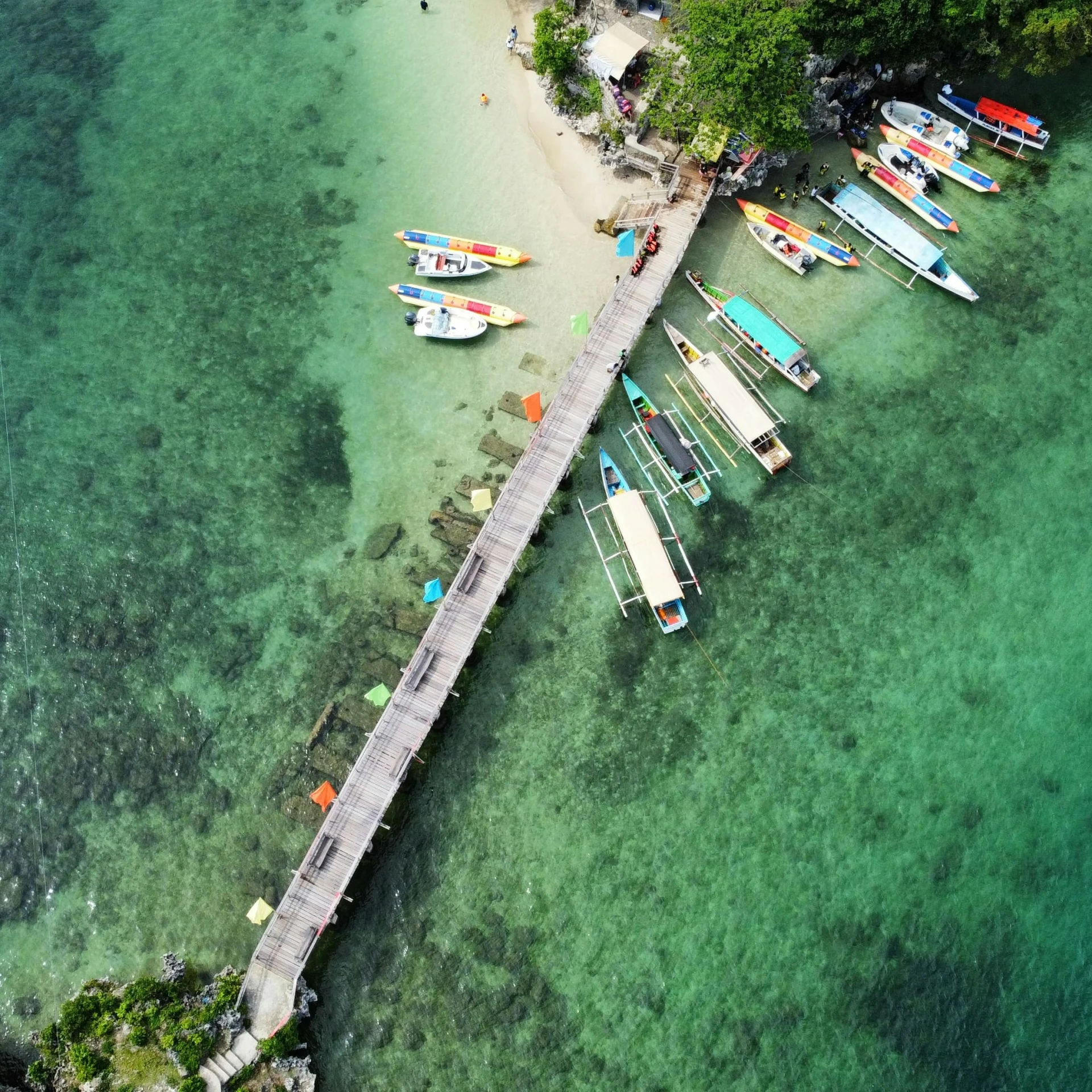 boats moored on a pier on a clear, turquoise sea