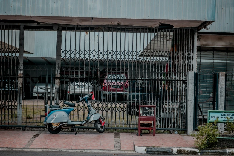 the fence behind the moped is made of iron