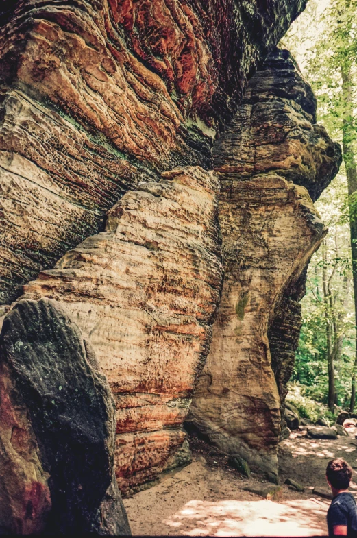 two people standing near a very large rock