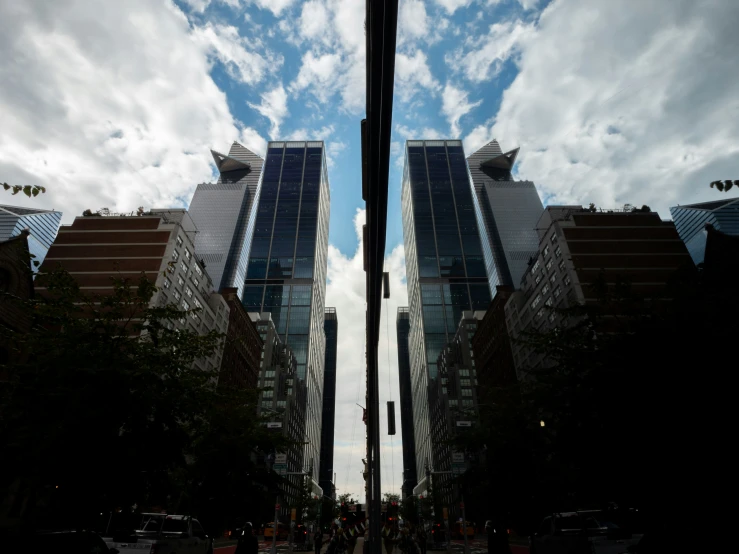 a group of buildings that have two very tall buildings with sky reflected in them