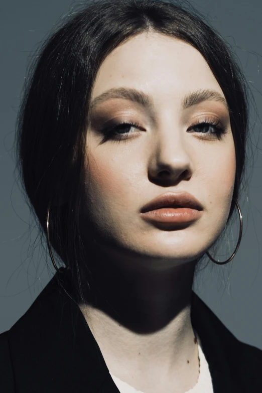 a woman with large hoops wearing a dark shirt and earrings