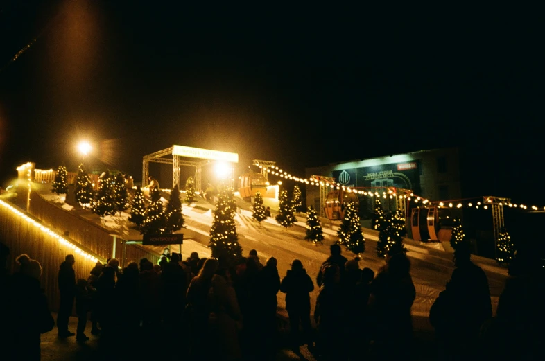 a crowd is gathered outside at night during the holiday season