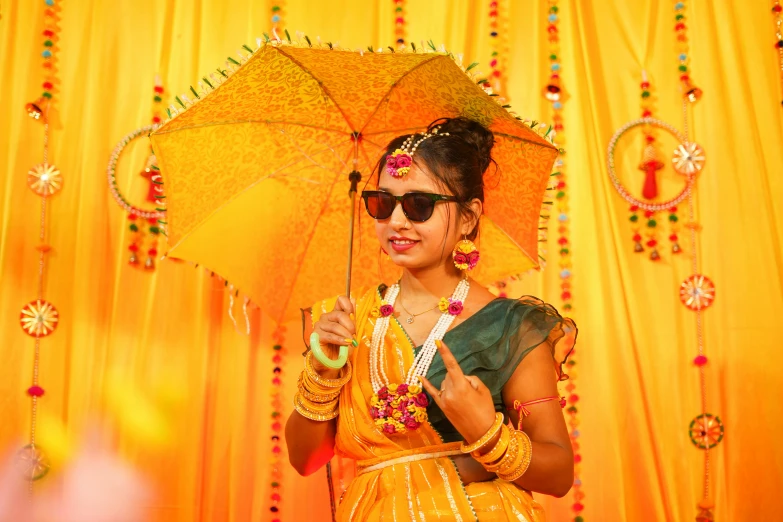 an indian woman in yellow is holding an umbrella