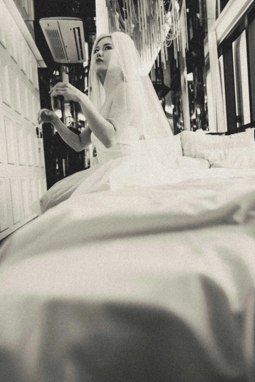 a bride sits on her bed with a veil flying in the wind