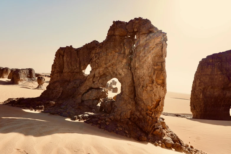 a rock formation stands in the sand near a desert