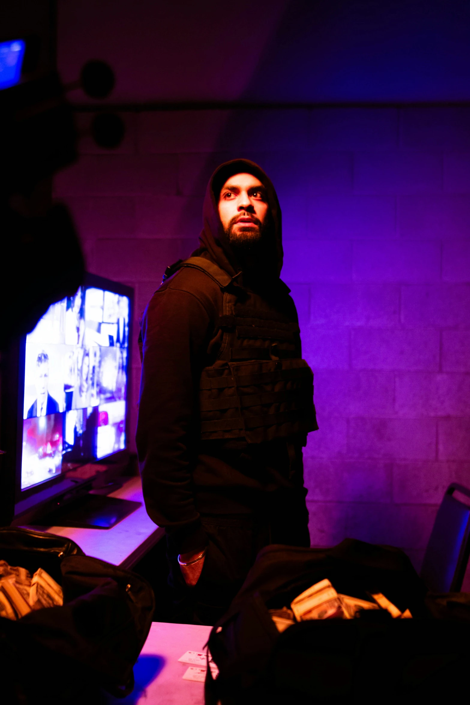 a man in dark clothing stands near two televisions