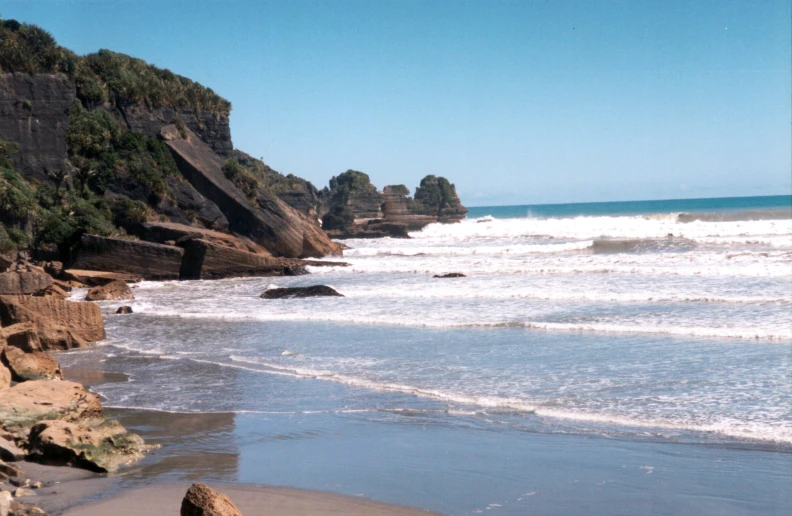 the coast next to the cliffs has water coming off of it