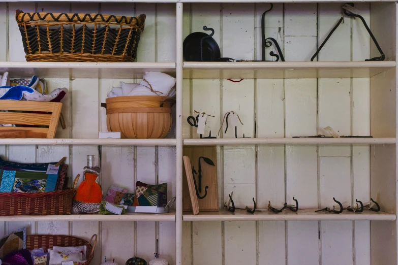 a white shelf holding baskets, umbrellas and other items