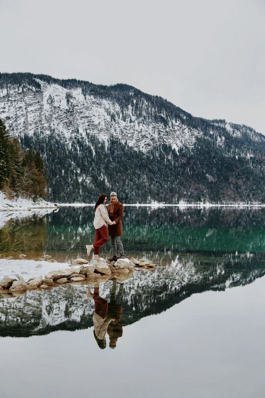 a couple of people stand in the water of a lake