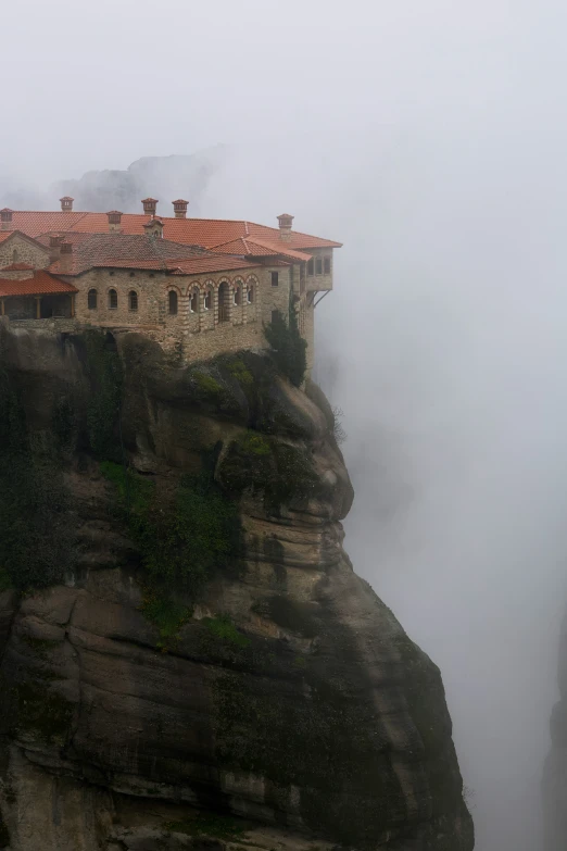 the building on top of the mountain is foggy