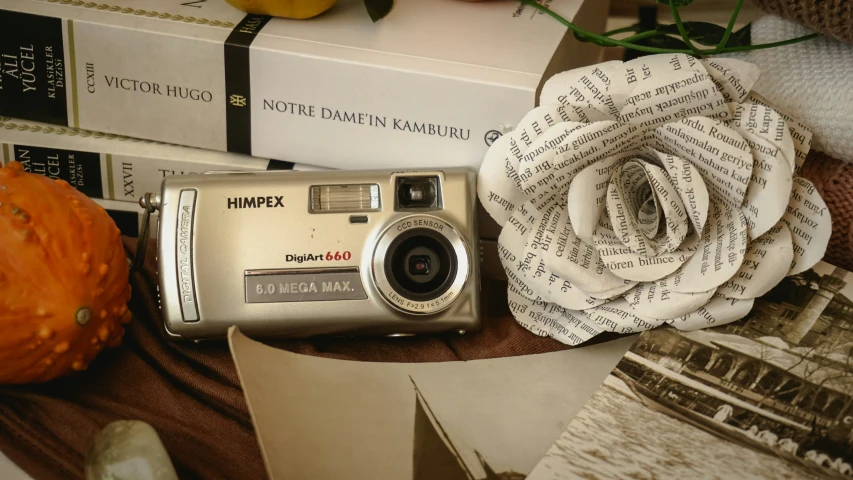 a digital camera is placed next to some books and pumpkins