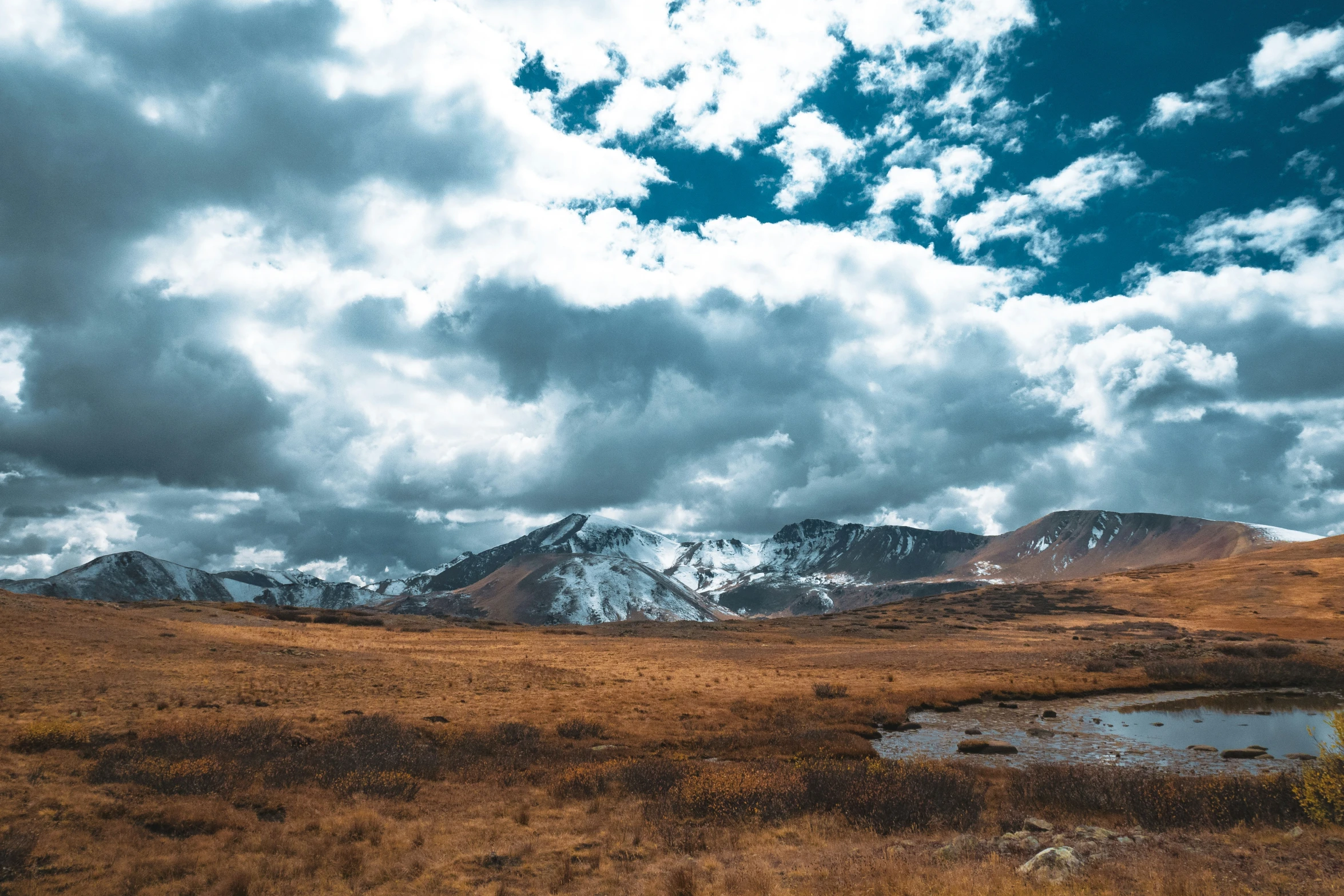 an empty mountain field with clouds moving across it