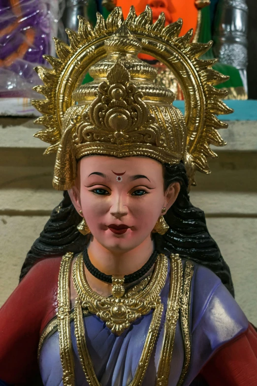 a statue with a face that is gold, wearing an elaborate headdress