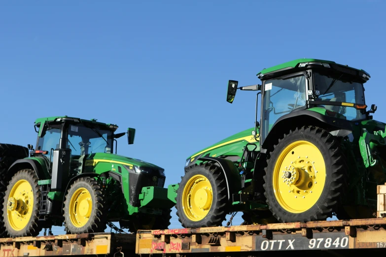 two large farm tractors sit on a flatbed trailer