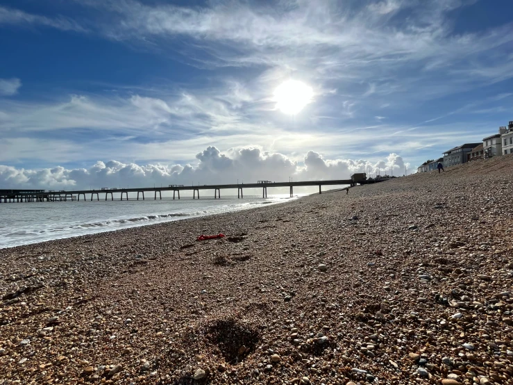 the sun shines in front of a long pier and ocean